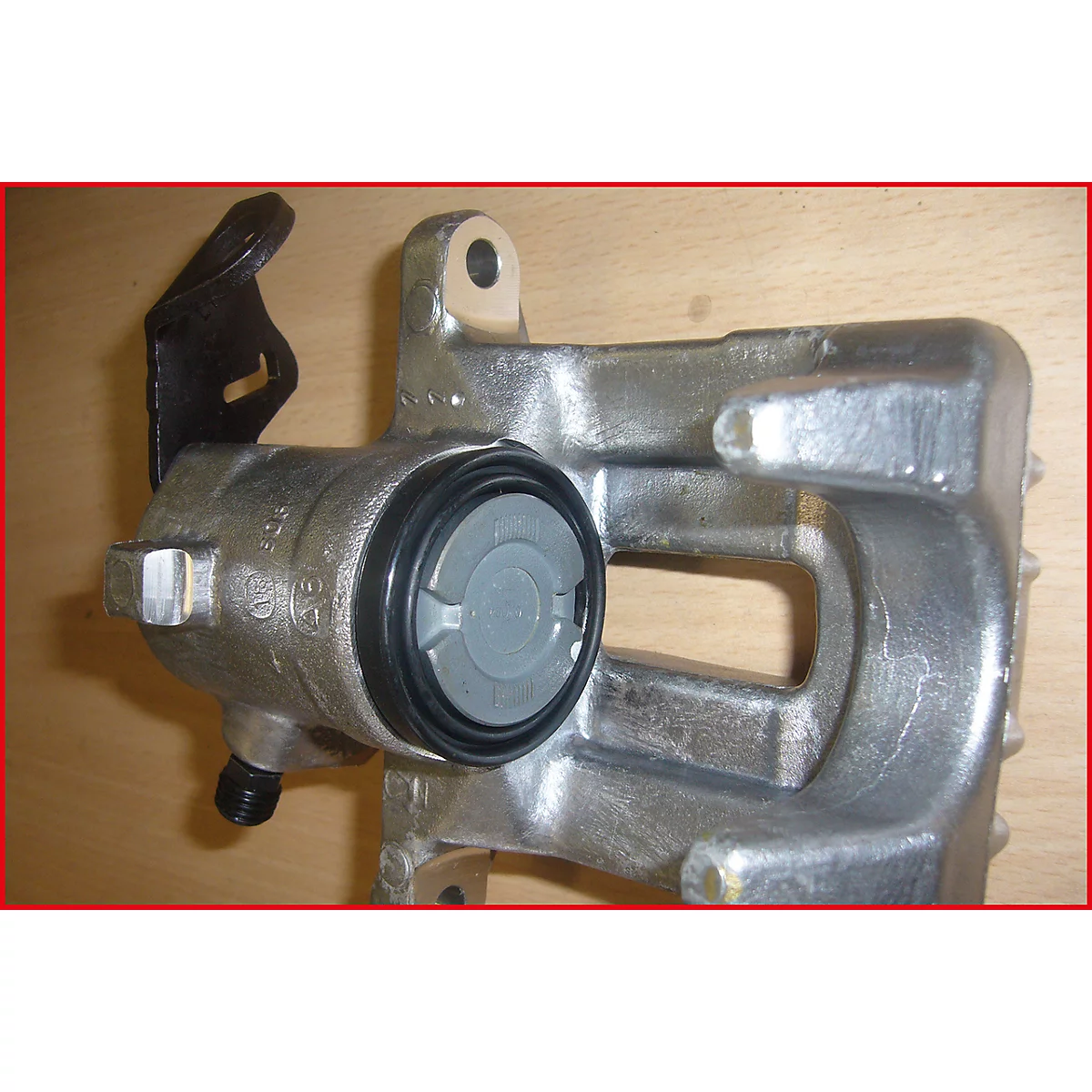 Grauer Bremssattel, Details: schwarze Dichtung, grauer Deckel. An der Seite ein schwarzes Anbauteil.